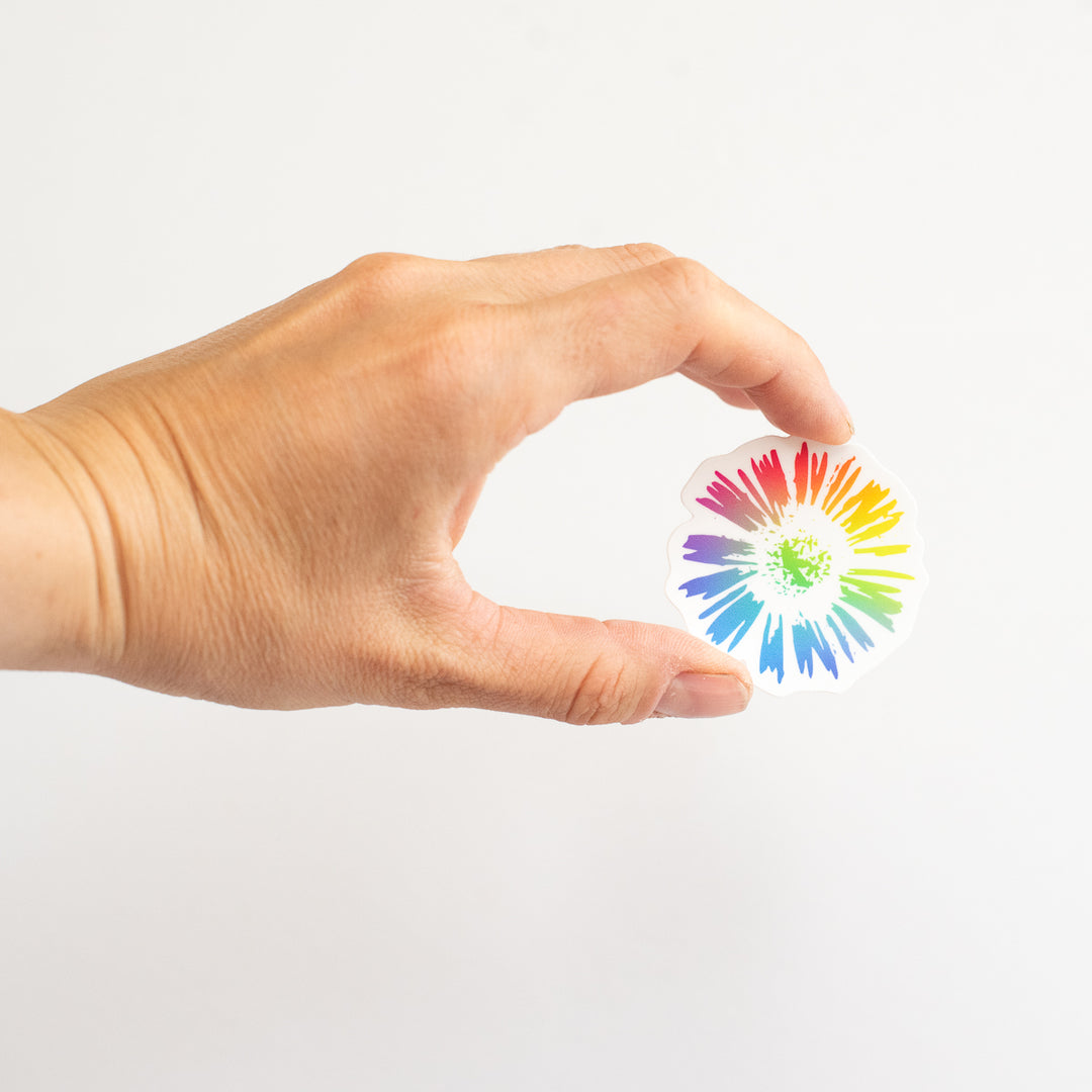 Hand holding a colorful floral sticker with a white background