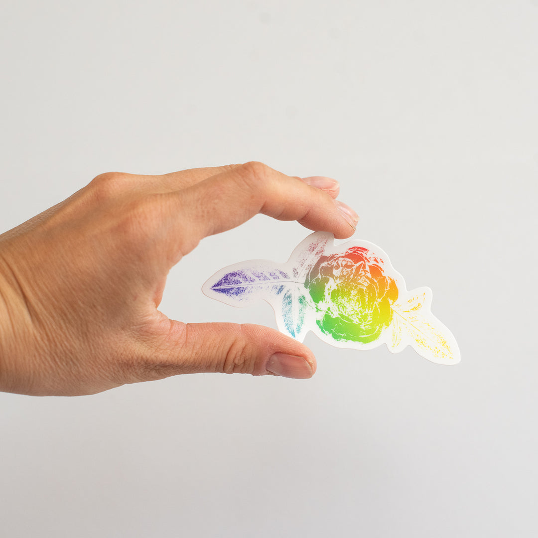 Hand holding a colorful vinyl sticker with a clear background