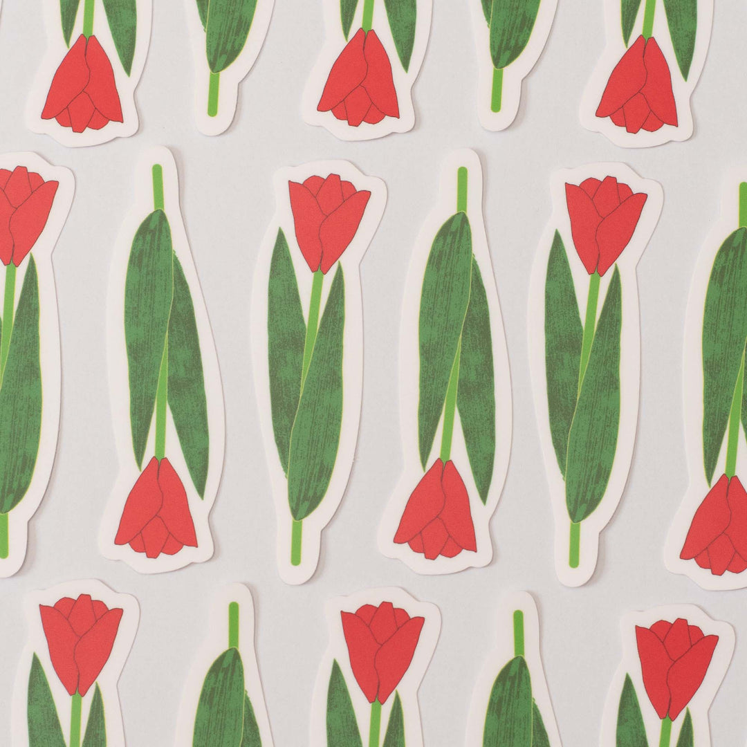 Pattern of red tulips with green leaves on a light gray background