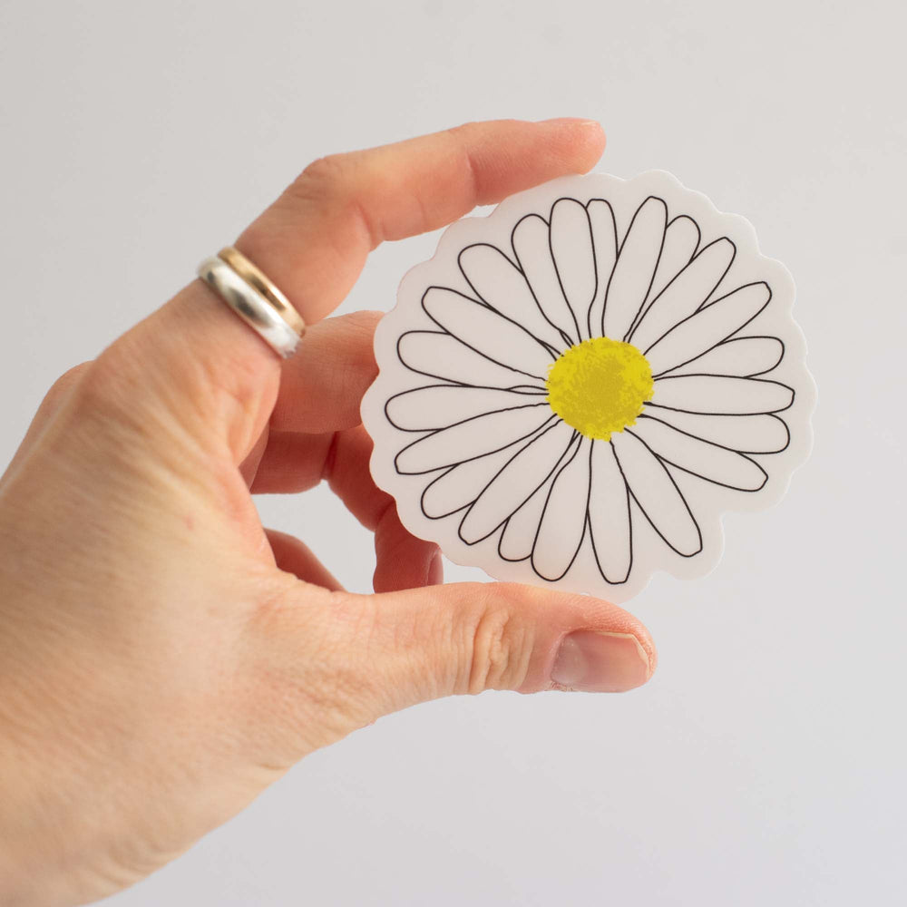Hand holding a sticker of a daisy with a white background