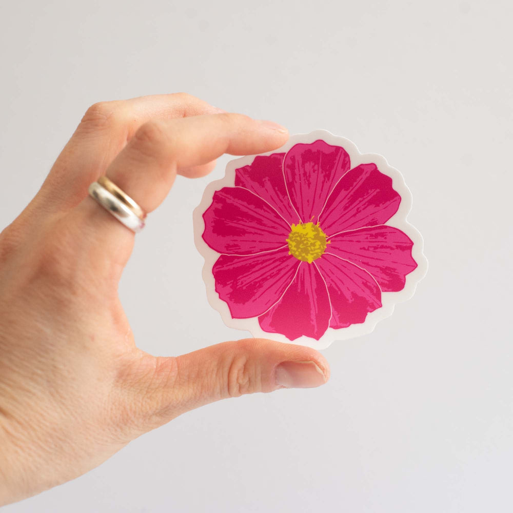 Hand holding a dark pink flower-shaped object against a light gray background